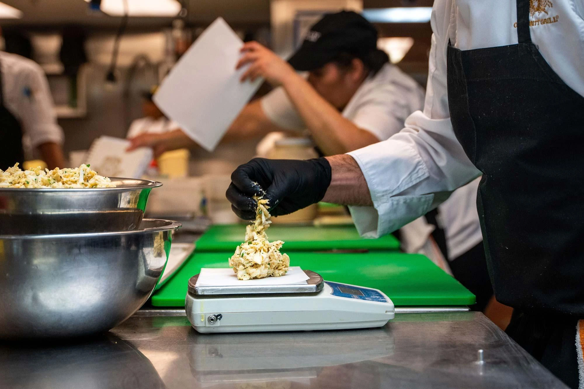 Kitchen team portioning meals by weight on a scale